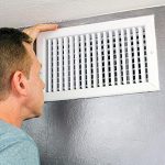 man looking inside an air vent