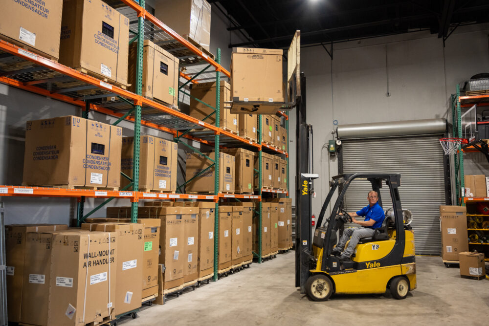 Forklift carrying an AC unit in a warehouse