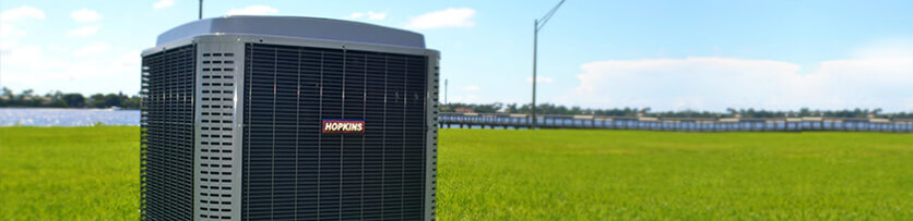 Hopkins brand outdoor AC unit with large mowed field in background.