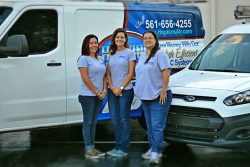 Hopkins Air Conditioning's friendly staff — three women standing together in front of Hopkins service truck, smiling.