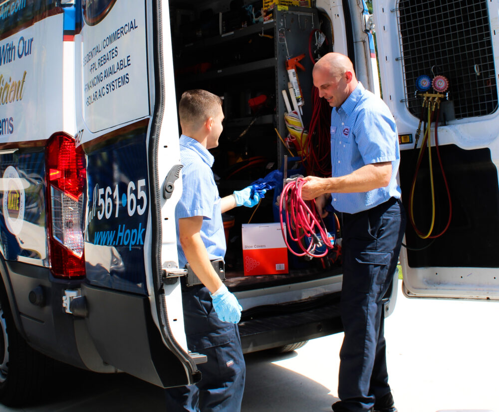 Two HVAC technicians getting supplies out of their truck