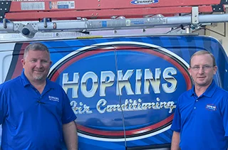 Hopkins Air Conditioning owners in front of a service truck.