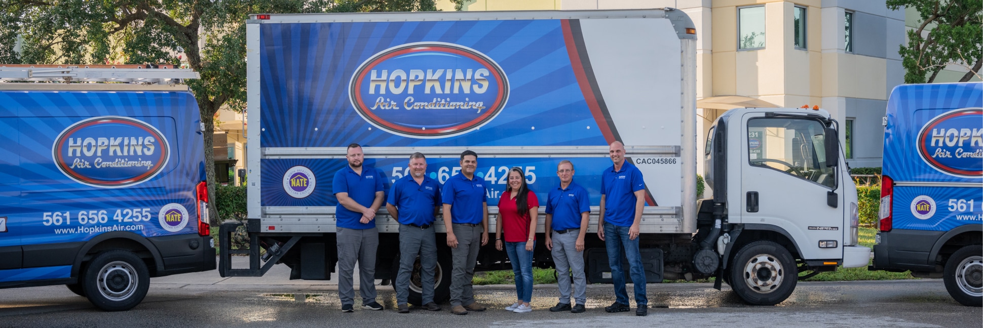 Hopkins Air Conditioning Technicians standing in a row in front of service trucks.